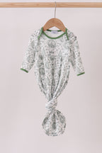 Green and white patterned baby outfit on a hanger against a light background